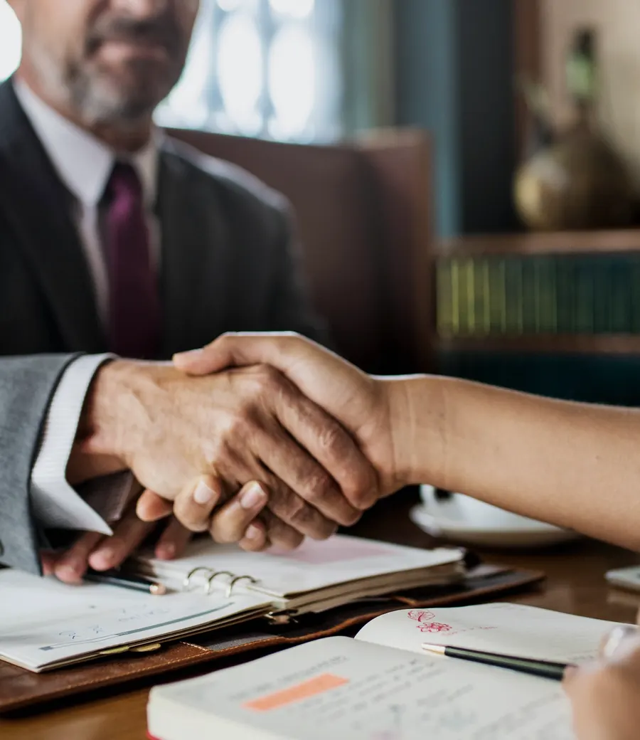 Attorney shaking hands with a client across a desk
